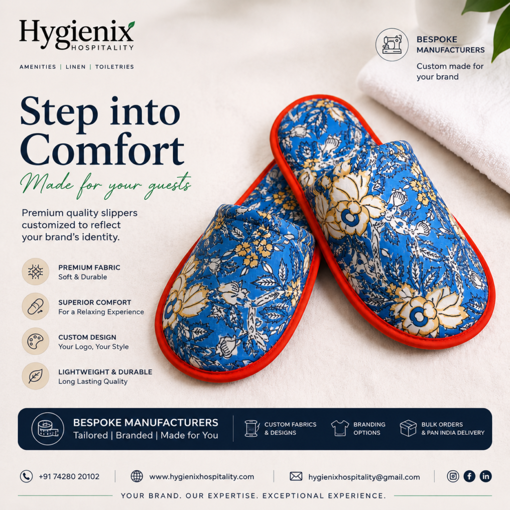 Premium custom hotel slippers with a blue floral fabric and red trim displayed on a soft white towel. The promotional banner by Hygienix Hospitality highlights bespoke manufacturing, premium fabric, superior comfort, custom branding, lightweight durability, bulk orders, and Pan India delivery for hotels, resorts, and hospitality businesses.