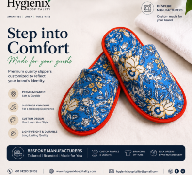 Premium custom hotel slippers with a blue floral fabric and red trim displayed on a soft white towel. The promotional banner by Hygienix Hospitality highlights bespoke manufacturing, premium fabric, superior comfort, custom branding, lightweight durability, bulk orders, and Pan India delivery for hotels, resorts, and hospitality businesses.